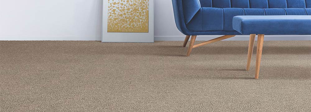 Tan patterned carpet with light blue couch and brown chair